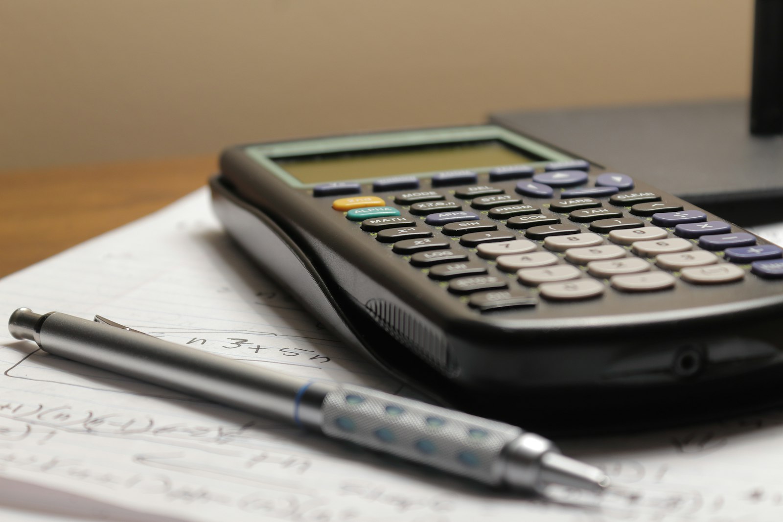 Une calculatrice et un stylo posés sur des notes manuscrites
